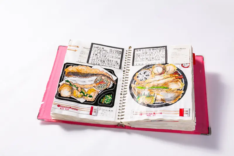 Caderno aberto com desenhos coloridos à mão de pratos de tempurá, acompanhados de anotações e notas fiscais coladas